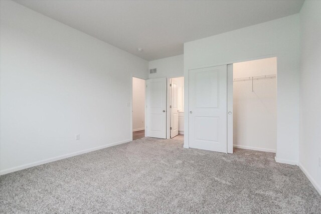 unfurnished bedroom with a closet, carpet flooring, visible vents, and baseboards