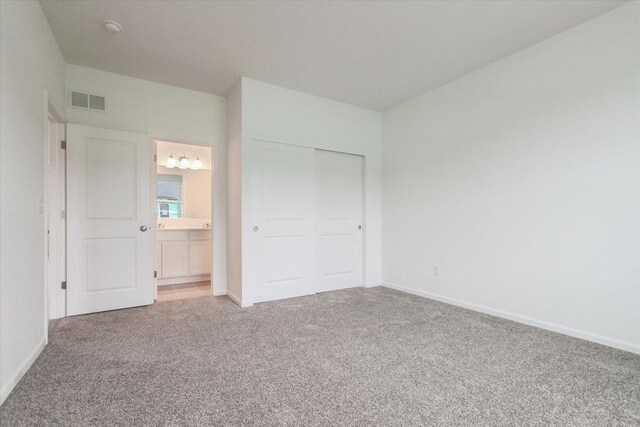 unfurnished bedroom featuring light colored carpet, visible vents, a closet, and baseboards