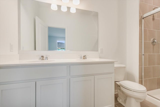 full bathroom with double vanity, a sink, toilet, and a shower stall