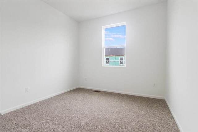 carpeted empty room featuring baseboards and visible vents
