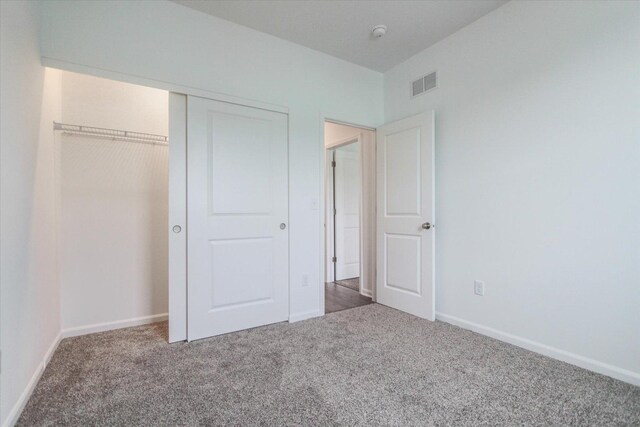 unfurnished bedroom featuring a closet, baseboards, visible vents, and carpet