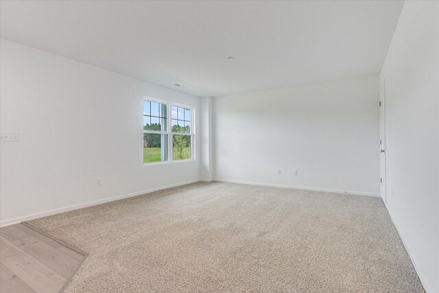 empty room featuring light carpet and baseboards