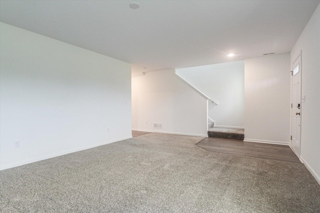 unfurnished living room with carpet flooring, baseboards, and stairway