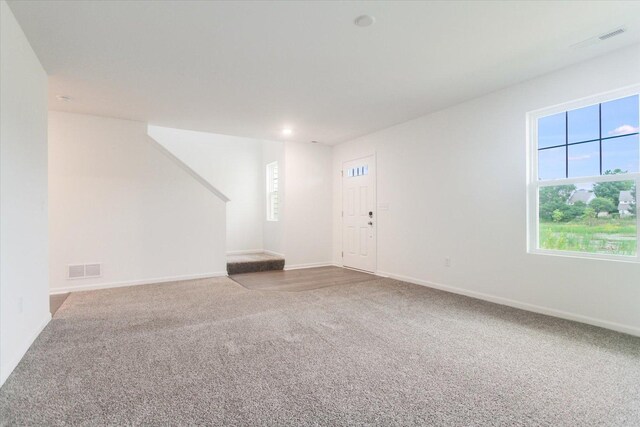 unfurnished living room featuring carpet, baseboards, stairs, and visible vents