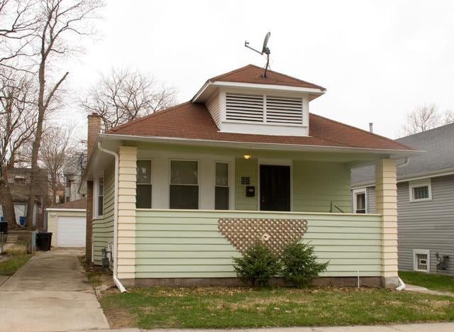 bungalow-style home featuring a chimney, a detached garage, and an outdoor structure