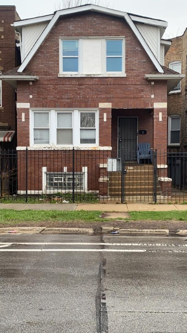 view of front of home with a fenced front yard, a gate, and brick siding