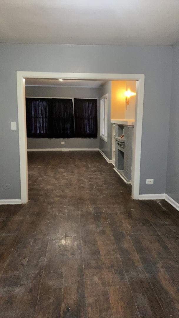 unfurnished living room featuring dark wood-style floors and baseboards
