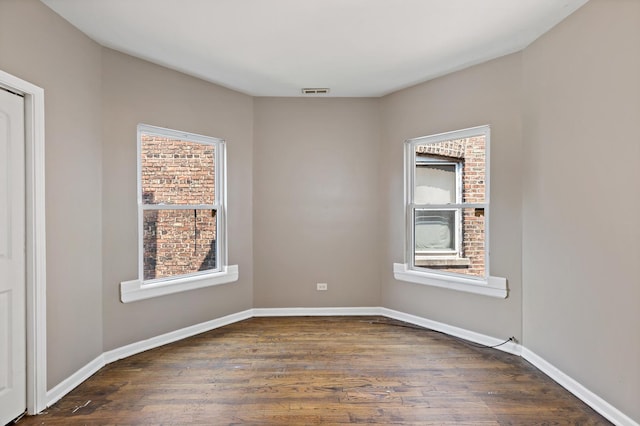 unfurnished room with visible vents, dark wood-style flooring, and plenty of natural light