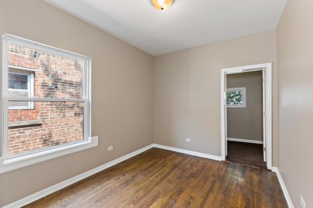 unfurnished room featuring dark wood-style flooring and baseboards