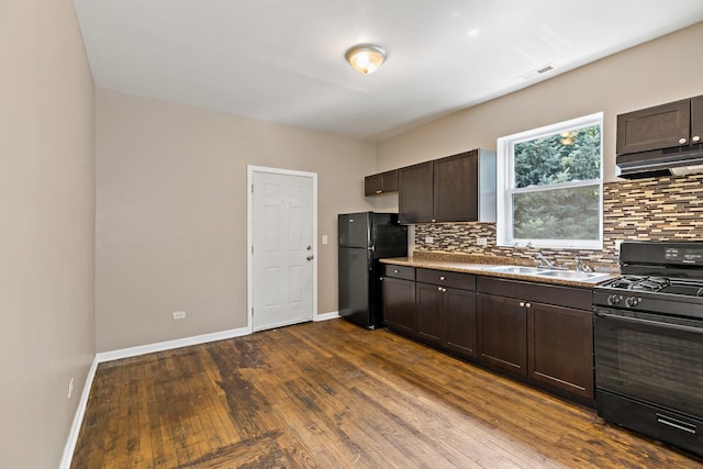 kitchen featuring tasteful backsplash, a sink, dark brown cabinets, under cabinet range hood, and black appliances