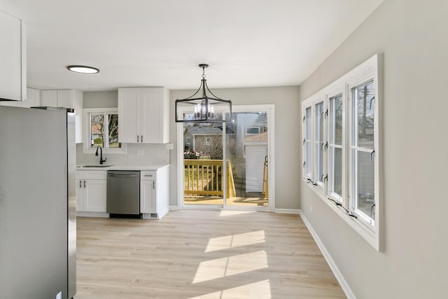753 Rogers Rd, Romeoville, IL 60446 - kitchen featuring white cabinetry, light countertops, a chandelier, a sink, and appliances with stainless steel finishes
