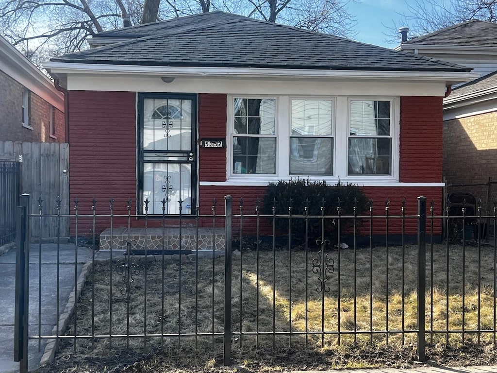 view of front of house featuring brick siding, a shingled roof, and fence
