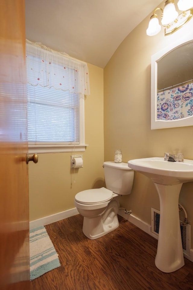 bathroom featuring toilet, lofted ceiling, wood finished floors, and baseboards