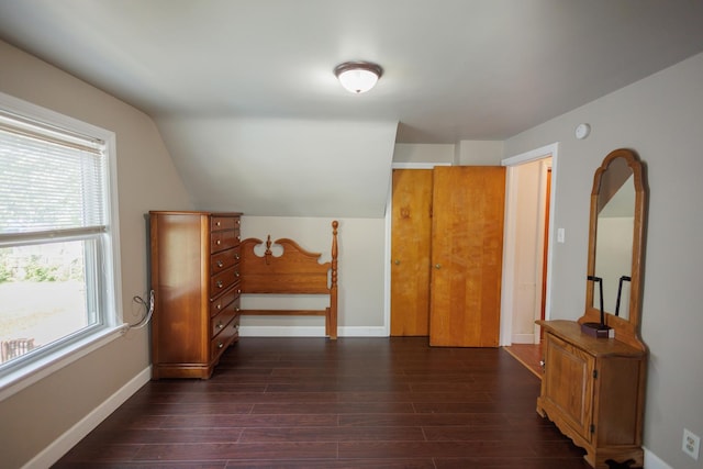 bonus room with dark wood finished floors, baseboards, and lofted ceiling