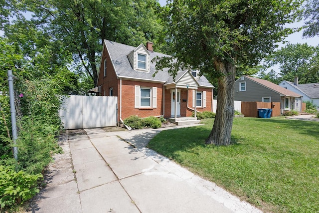 view of front of house featuring a gate, a chimney, fence, brick siding, and a front lawn