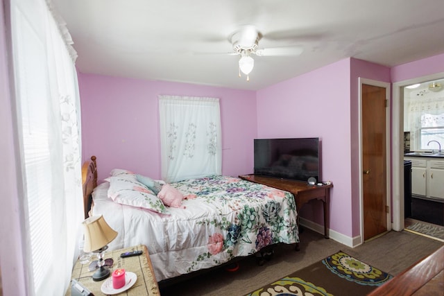 carpeted bedroom with baseboards, a sink, and a ceiling fan