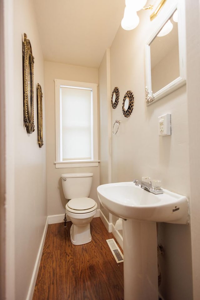 bathroom with baseboards, visible vents, wood finished floors, and toilet