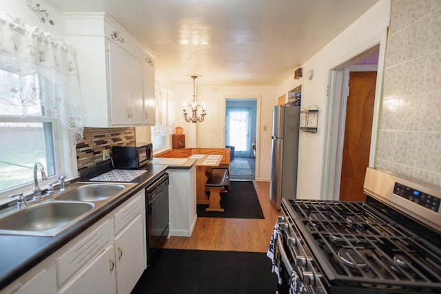 kitchen with dark countertops, black appliances, a sink, and white cabinets
