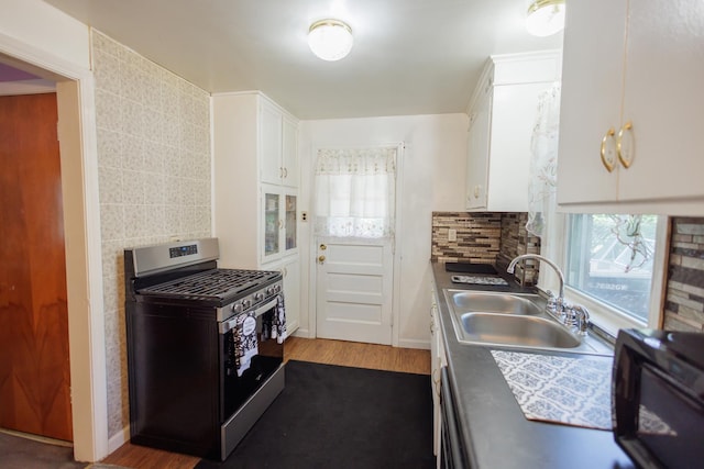 kitchen with backsplash, a sink, white cabinetry, dishwashing machine, and gas stove