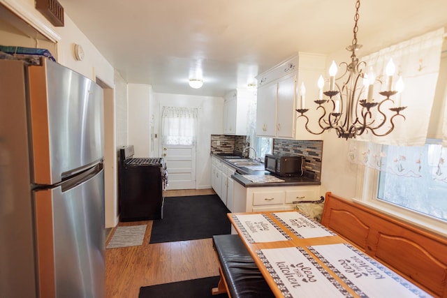 kitchen with dark wood-style flooring, white cabinets, decorative backsplash, and freestanding refrigerator