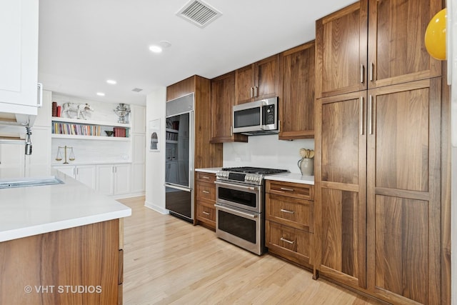 21 E Huron St Unit 1806, Chicago, IL 60611 - kitchen featuring stainless steel appliances, light countertops, light wood-type flooring, brown cabinetry, and a sink