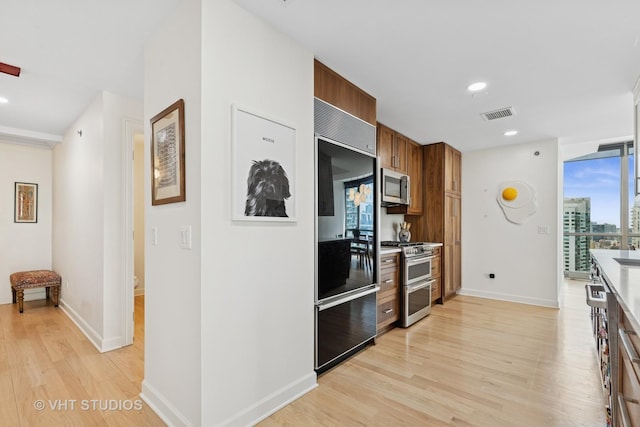 21 E Huron St Unit 1806, Chicago, IL 60611 - kitchen featuring stainless steel appliances, light wood finished floors, baseboards, brown cabinets, and recessed lighting