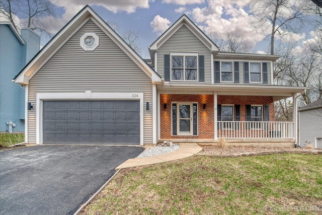 traditional-style home featuring an attached garage, brick siding, a front lawn, driveway, and covered porch