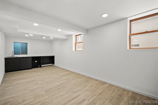 spare room with baseboards, recessed lighting, light wood-style floors, and a sink