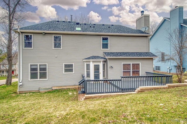 back of property with a lawn, a wooden deck, and roof with shingles