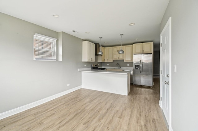 kitchen with baseboards, wall chimney exhaust hood, appliances with stainless steel finishes, a sink, and light wood-type flooring