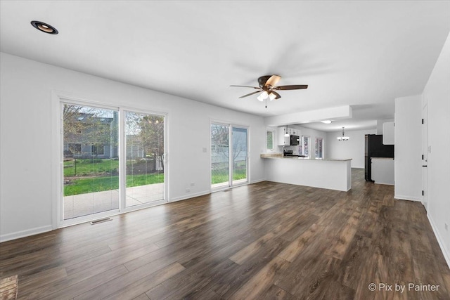 413 Edinburgh Ln, West Dundee, IL 60118 - unfurnished living room featuring baseboards, ceiling fan with notable chandelier, dark wood-style flooring, and visible vents