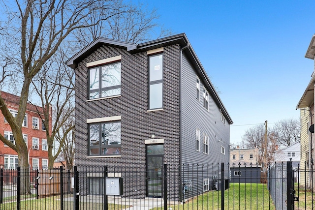 view of front of house featuring brick siding, a fenced front yard, and a front lawn
