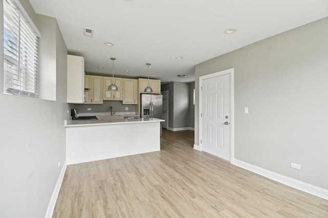 kitchen featuring a peninsula, stainless steel fridge with ice dispenser, baseboards, and visible vents