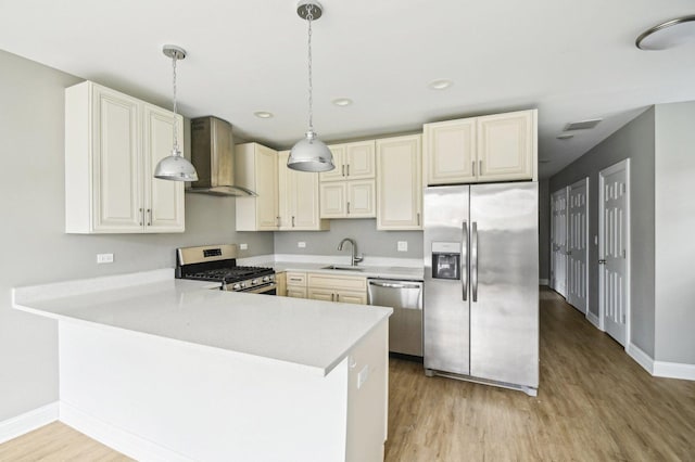 kitchen with a sink, light wood finished floors, stainless steel appliances, wall chimney range hood, and visible vents