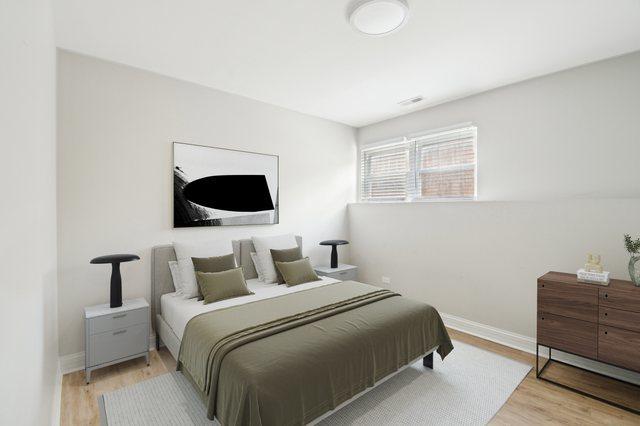 unfurnished bedroom with a closet, baseboards, visible vents, and light wood-style floors