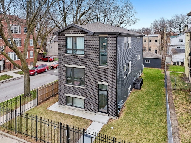 view of front of property with a residential view, brick siding, a fenced front yard, and a front lawn