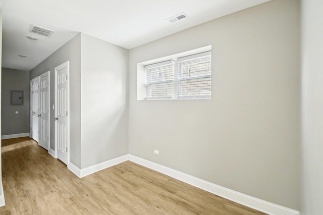 unfurnished room with baseboards, visible vents, and wood finished floors