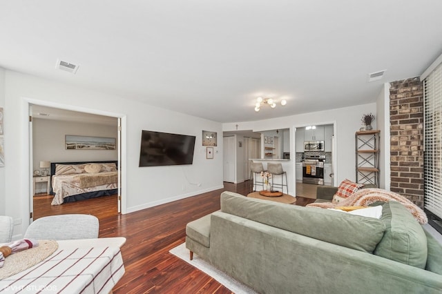 living area featuring baseboards, visible vents, and wood finished floors