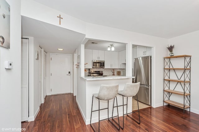 kitchen with dark wood-style flooring, stainless steel appliances, tasteful backsplash, and light countertops