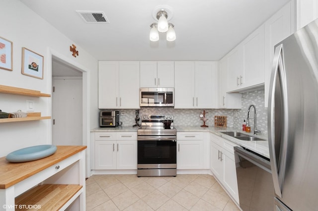 kitchen featuring a sink, tasteful backsplash, stainless steel appliances, and visible vents