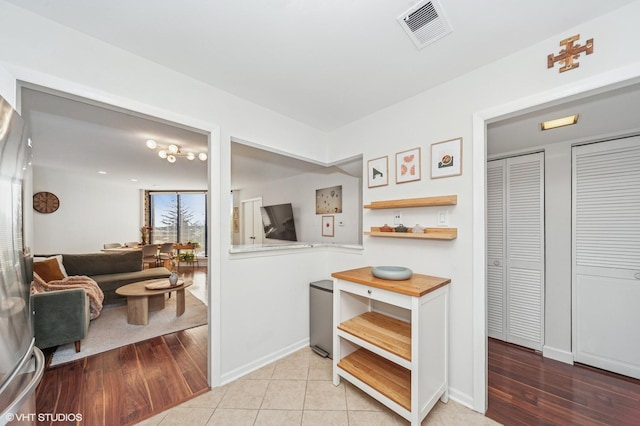 hallway featuring visible vents, baseboards, and wood finished floors