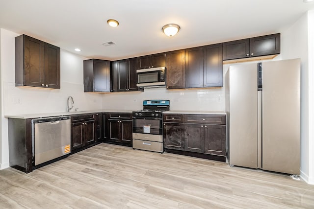 kitchen featuring dark brown cabinetry, light countertops, stainless steel appliances, and light wood finished floors