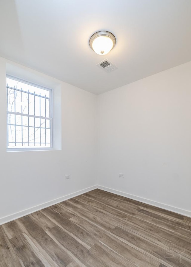 empty room featuring baseboards, visible vents, and wood finished floors