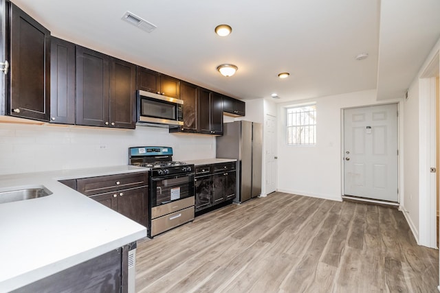 kitchen with light countertops, visible vents, light wood finished floors, stainless steel appliances, and dark brown cabinets