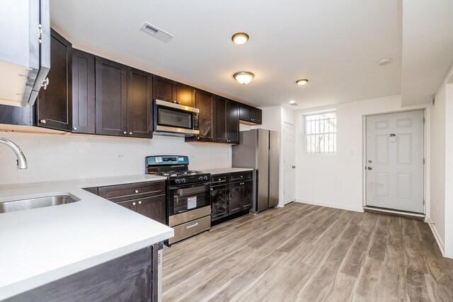 kitchen with light countertops, a sink, stainless steel appliances, light wood-style floors, and dark brown cabinets
