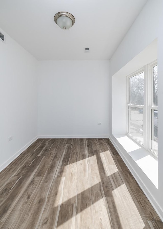 unfurnished room featuring wood finished floors, baseboards, and visible vents