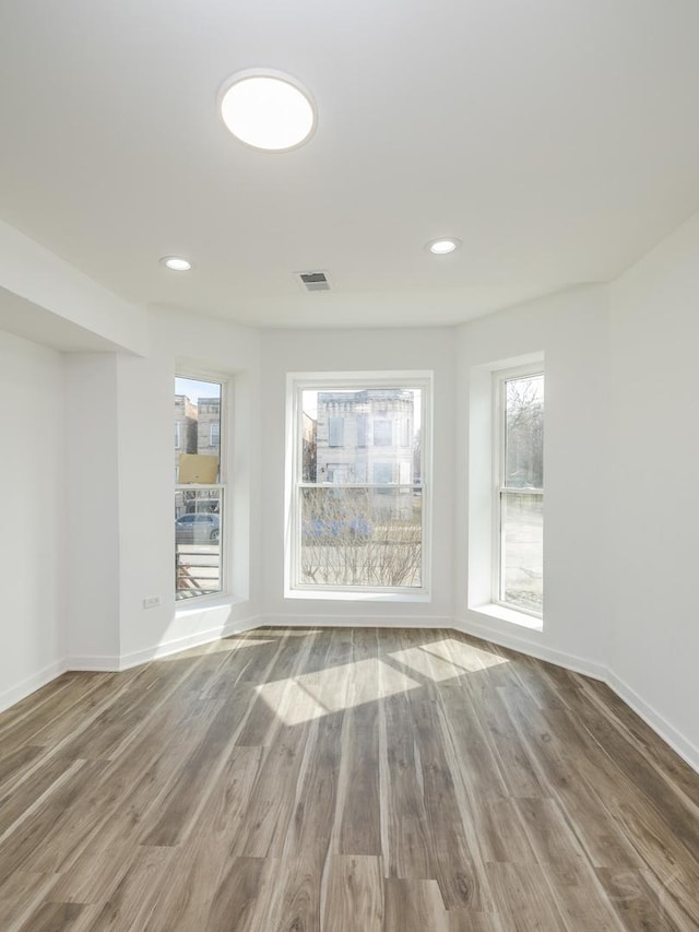 unfurnished room featuring baseboards, visible vents, wood finished floors, and recessed lighting