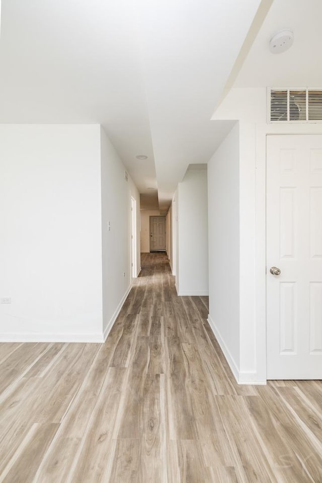 hallway with light wood-type flooring, baseboards, and visible vents