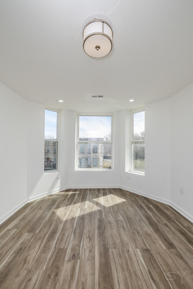 empty room featuring visible vents, baseboards, and wood finished floors