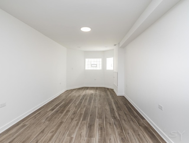 spare room featuring baseboards and dark wood-type flooring